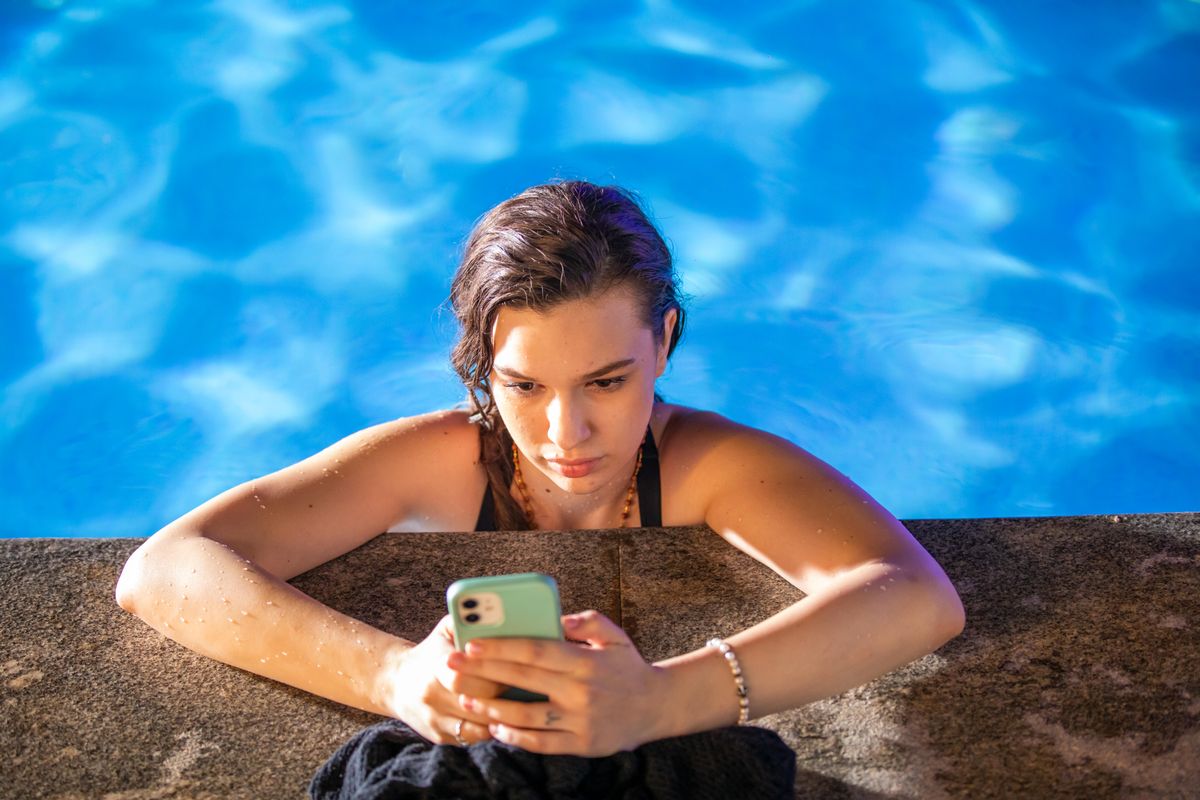 Mlada žena gleda u mobitel i smiješi se poruci.